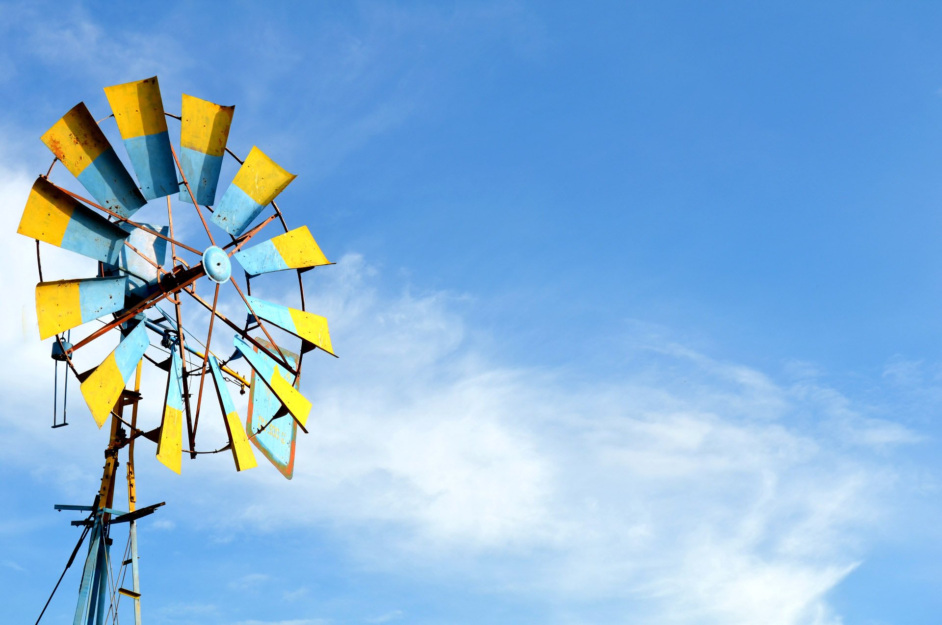 A yellow and blue windmill over the blue sky.
